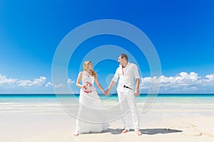 Happy bride and groom having fun on a tropical beach. Wedding an