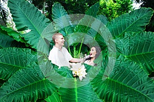 Happy bride and groom having fun on a tropical jungle. Wedding a