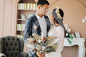 Happy bride and groom holding a bouquet of wedding flowers, Happy young couple, Bride and groom posing and looking at each other