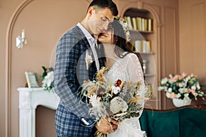 Happy bride and groom holding a bouquet of wedding flowers, Happy young couple, Bride and groom posing and looking at each other