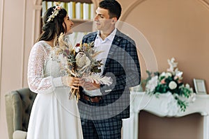 Happy bride and groom holding a bouquet of wedding flowers, Happy young couple, Bride and groom posing and looking at each other