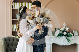 Happy bride and groom holding a bouquet of wedding flowers, Happy young couple, Bride and groom posing and looking at each other