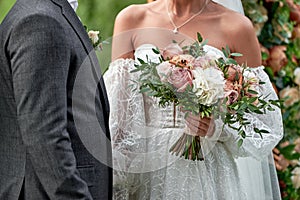 Happy bride and groom holding hands on wedding ceremony, copy space. Wedding couple in love, newlyweds. Bridal bouquet.