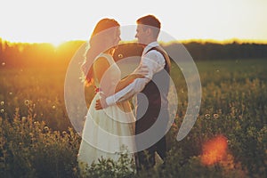 Happy bride and groom hug each other in the park at sunset. Wedding. Happy love concept