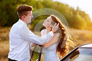 Happy bride and groom hugging near car