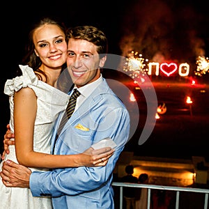 Happy bride and groom hugging smiling on background firework