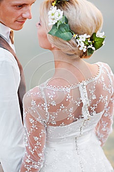 Happy bride and groom look at each other. Bride in white dress and wreath on head. Close-up