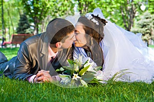 Happy bride and groom lying on grass