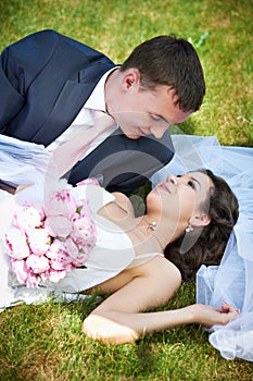 Happy bride and groom lying on grass