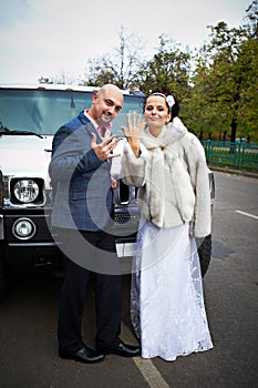 Happy bride and groom near wedding limo