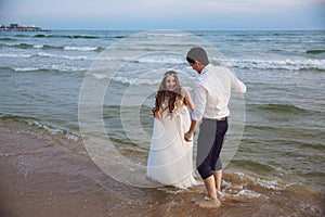 Happy bride and groom run along ocean shore. Newlyweds having fun at wedding day on tropical beach