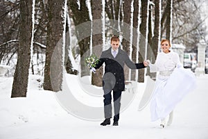 Happy bride and groom running in winter park