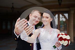 Happy bride and groom showing their rings on hands