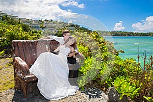 Happy bride and groom sitting on the bench in front of beautiful