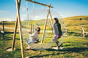 Happy bride and groom sitting on a swing in the mountains. The concept of marriage and lifestyle.