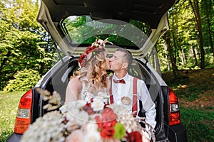 Happy bride and groom sitting in the trunk of a car