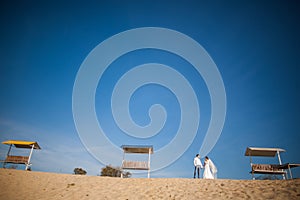 Happy bride, groom standing on beach, kissing, smiling, laughing in their honeymoon.