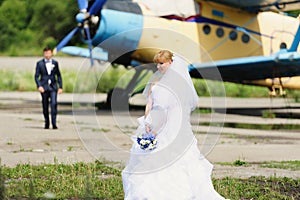 Happy bride and groom on their wedding near the old airplane