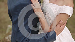 Happy bride and groom. Touching hands. The groom embraces the bride with a bouquet. Tears of happiness. close-up