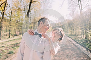 Happy bride standing behind fixing blue bow tie of her smiling groom in white shirt