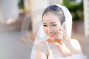 Happy bride talking on cell phone in wedding dress