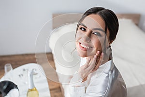 happy bride touching face while smiling