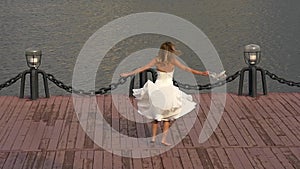 Happy bride twisting in dance on pier