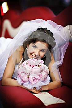 Happy bride with wedding bouquet in limo