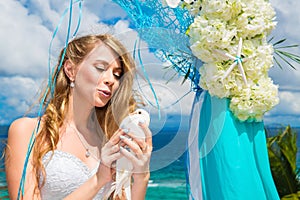 The happy bride with white doves on a tropical beach under palm