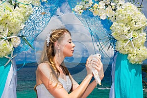 The happy bride with white doves on a tropical beach under palm