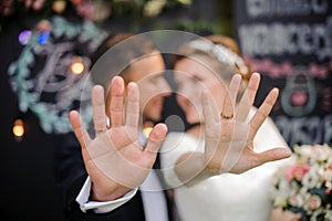 Happy bridegroom and bride showing wedding rings on their fingers