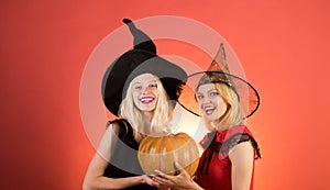 Happy brightful positive moments of two stylish girlson orange background. Surprise. Halloween girls through hole in