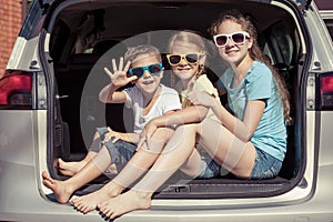 Happy brother and his two sisters are sitting in the car at the