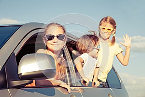 Happy brother and his two sisters are sitting in the car