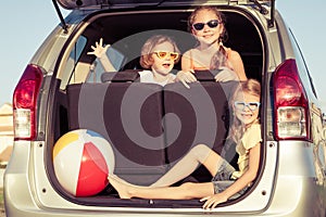 Happy brother and his two sisters are sitting in the car