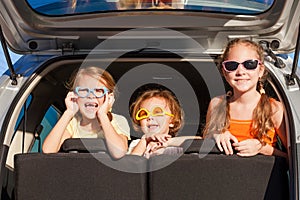 Happy brother and his two sisters are sitting in the car