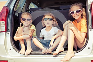 Happy brother and his two sisters are sitting in the car