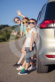 Happy brother and his two sisters are standing near the car at the day time