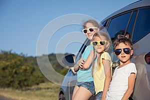 Happy brother and his two sisters are standing near the car at the day time