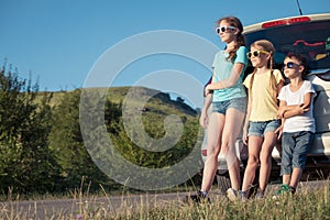 Happy brother and his two sisters are standing near the car at the day time