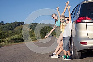 Happy brother and his two sisters are standing near the car at the day time