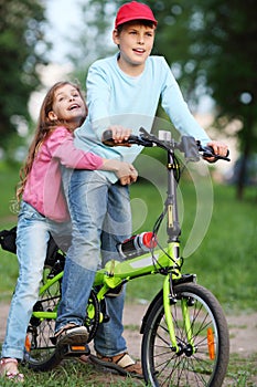 Happy brother and sister ride bicycle and sing in