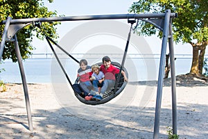 Happy brothers, children on the beach, swinging in a big round swing