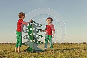 Happy brothers are playing with paper tree