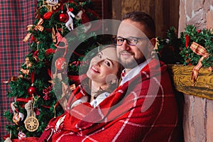 Happy brunette bride and gorgeous groom in the cozy plaid. Christmas tree.