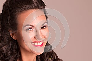 Happy brunette with hairdo and make up smiles in studio, pin-up