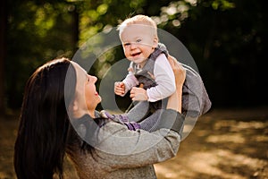 Happy brunette mother playing with a laughing baby daughter