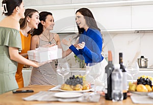 Happy brunette receiving unexpected gift from besties at birthday bash