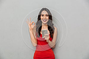 Happy brunette woman in casual clothes holding smartphone