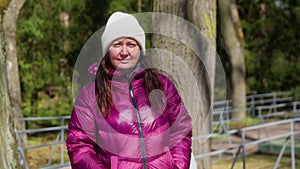 Happy brunette woman enjoys walking in park on sunny cold day early spring.